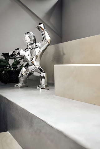 a chrome gorilla sculpture on modern stairs