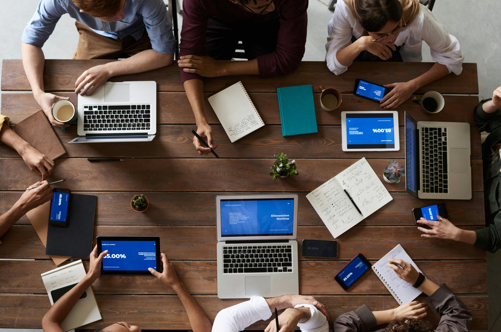 Office Table with Laptops, Notepads and Employees