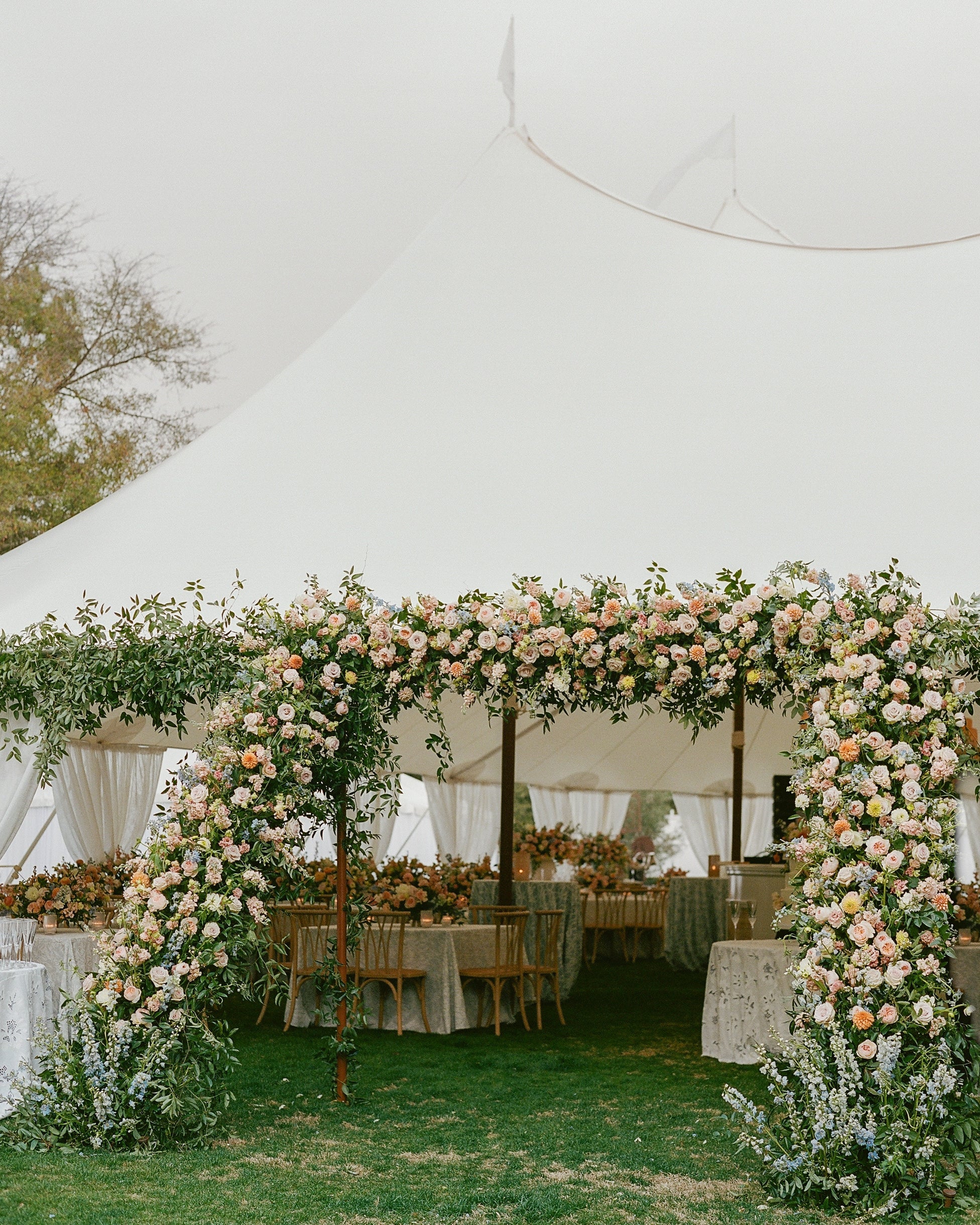 Outdoor wedding reception under a white text with pastel color flowers