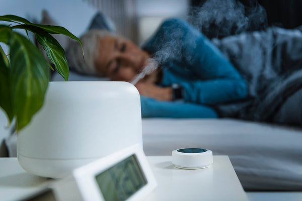 Beautiful Older Woman sleeping peacefully in bed with steam billowing out of her humidifier