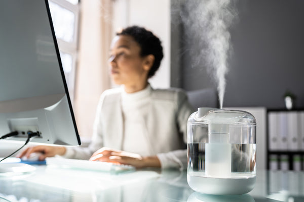 Beautiful Woman of Colour working in an office with steam billowing out of her humidifier