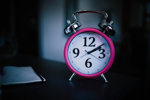 A pink and white round alarm clock