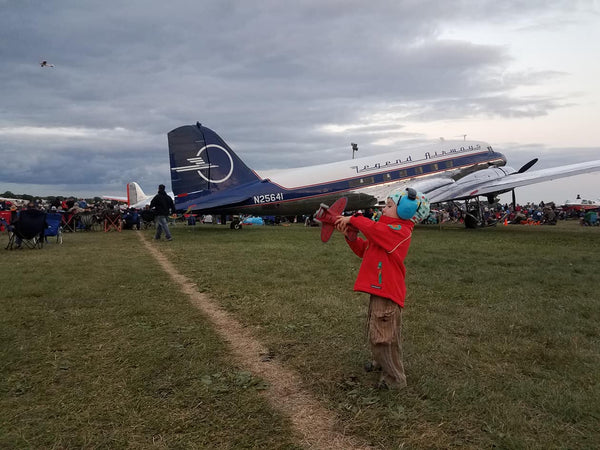 child with toy airplane in front of dc airplane
