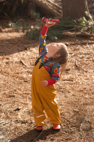 child flying a toy car in the woods