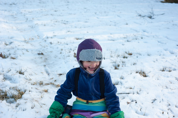 girl on a sled on a snowy hill in villervalla snow gear 