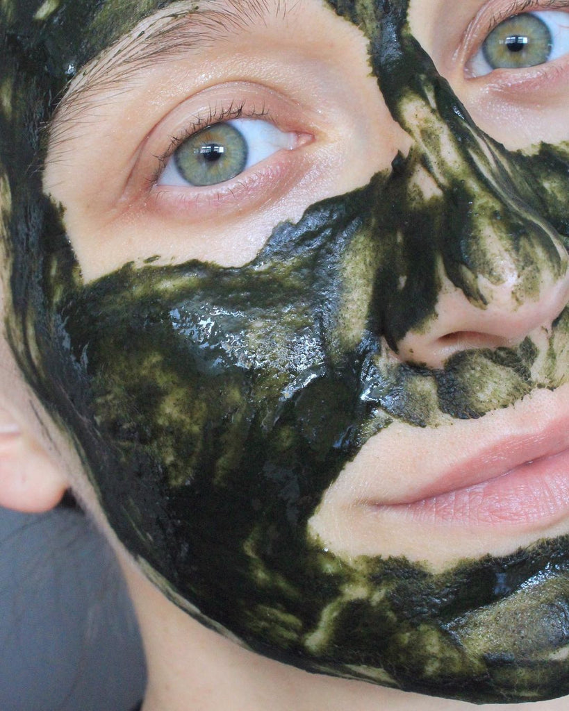 Masquage selfie. Une fille aux yeux verts porte un masque facial vert vif, riche et profond. Le masque est mélangé avec de l'eau et du miel. Le masque est à base de poudre de neem. Voici le masque facial Catharsis de Earthwise Beauty.