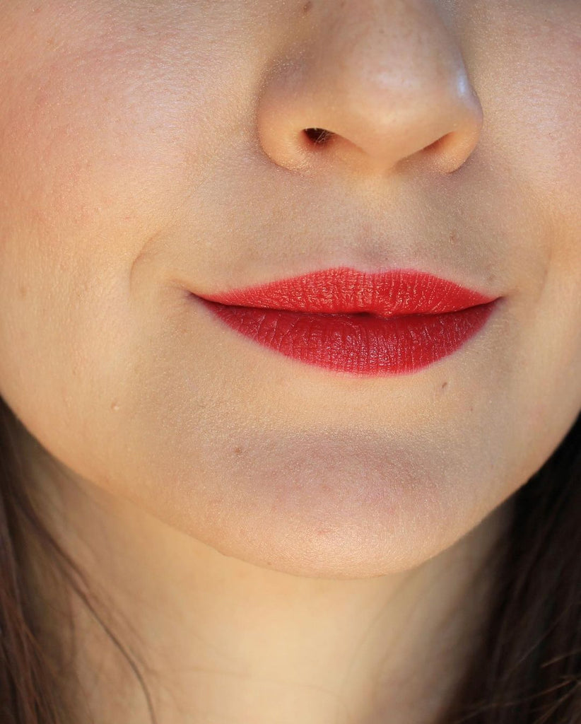 A close up of a girl and her face. It's all about the lips and her lipstick. Wearing a classic red color, this is the shade New York. This is Velvet Lip Creme, a matte lipstick by a Canadian brand Saint Cosmetics.