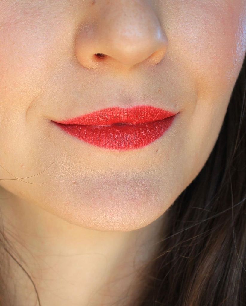A close up of a girl and her face. It's all about the lips and her lipstick. Wearing an orange red color, this is the shade Singapore. This is Velvet Lip Creme, a matte lipstick by a Canadian brand Saint Cosmetics.