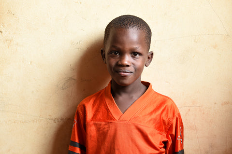 Smiling Ugandan boy wearing orange shirt