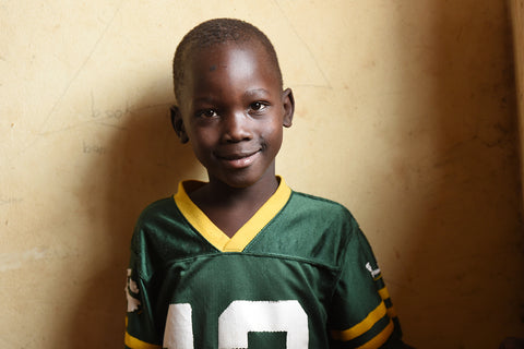 Smiling Ugandan boy wearing green football jersey