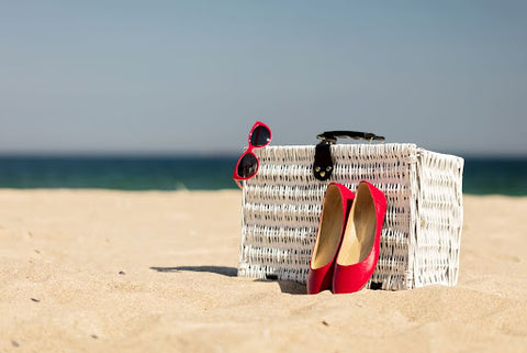 Red flats standing against a white picnic basket at the beach