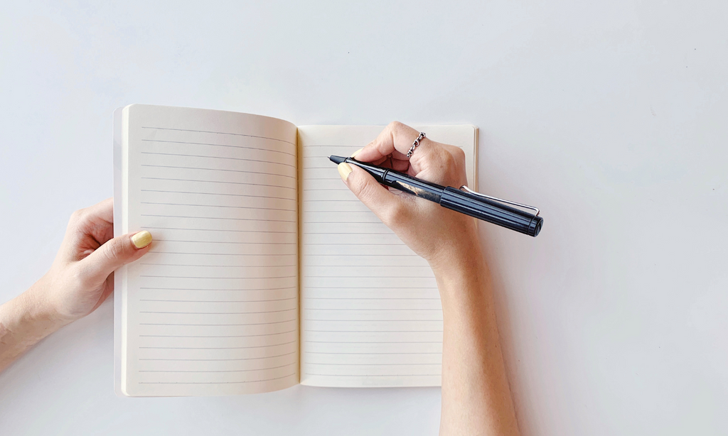 woman's hand writing in journal