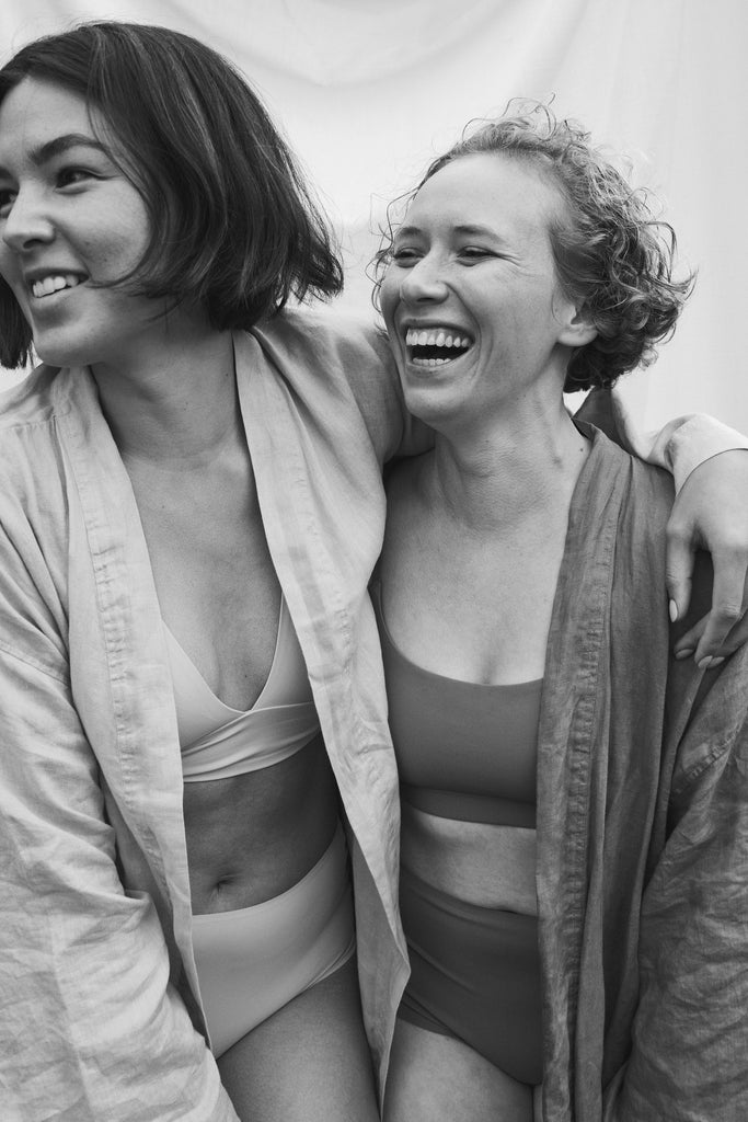 two woman embracing and laughing in black and white showing self-love and friendship