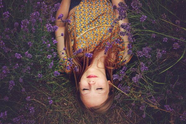 pretty girl relaxed and smiling, laying on a bed of grass and lavender flowers