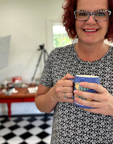 Mrs Red in black white dress with cup of tea