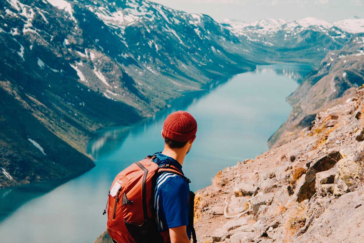 Hiker on high ridge looking down at lake.