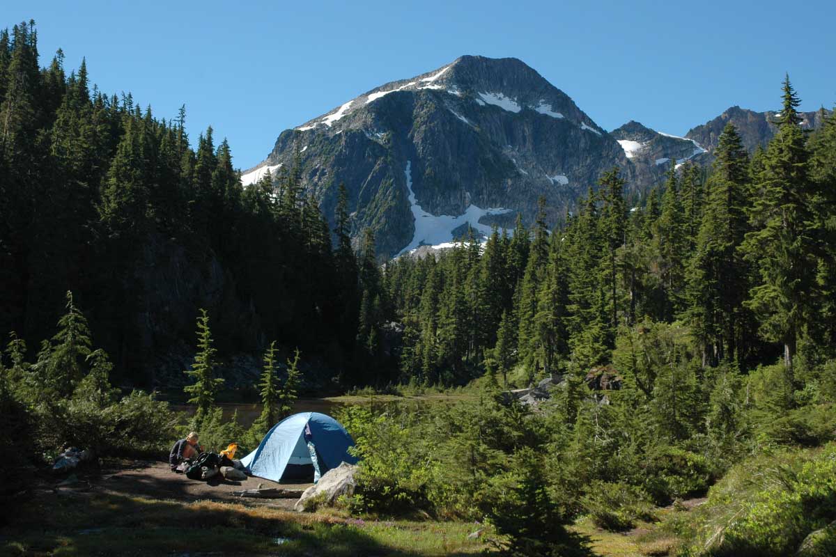 Campsite with tent with beautiful mountains in the background.