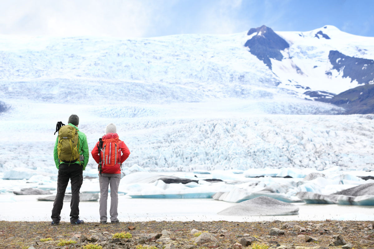 A stunning winter hike with a couple admiring ice chunks and a snowy mountain view.