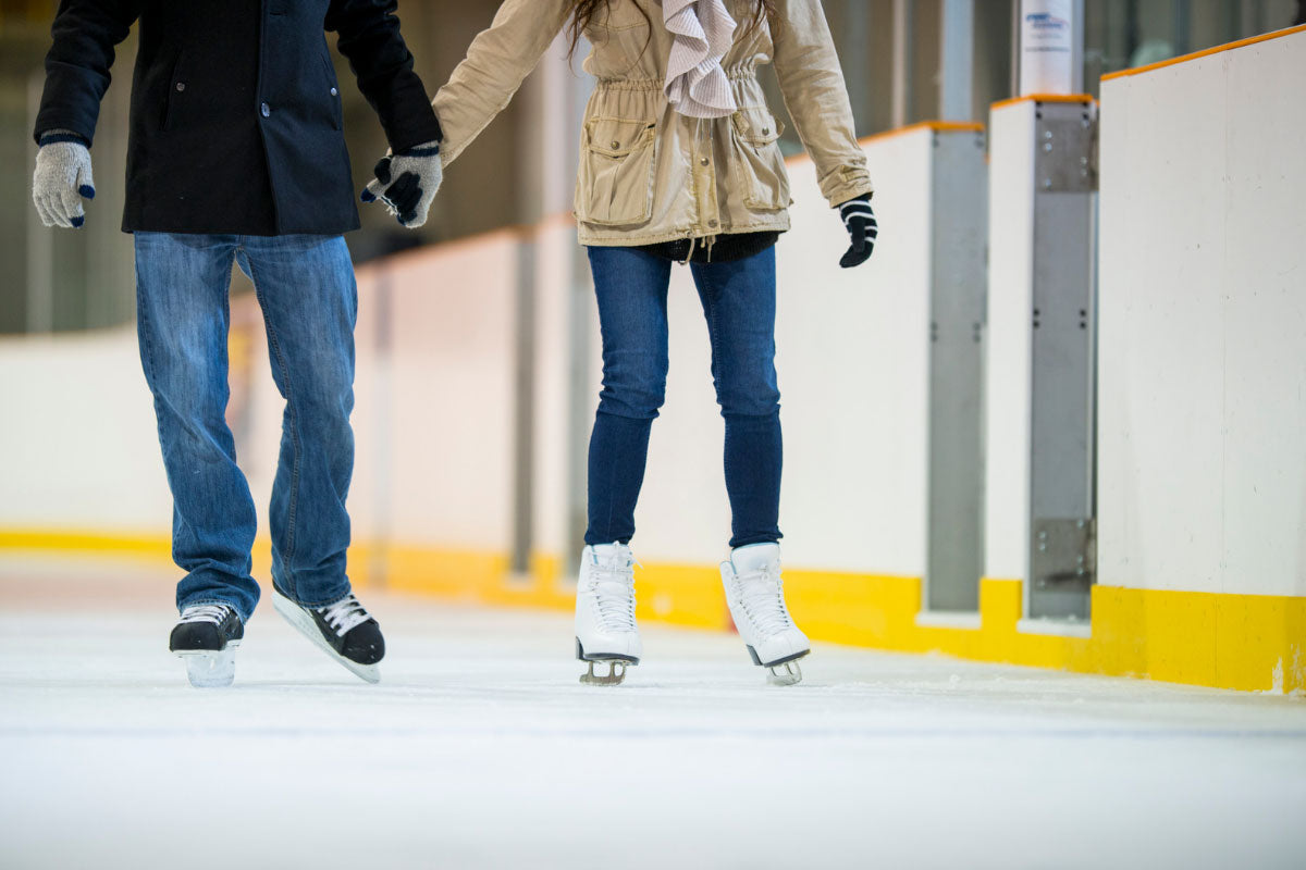 Ice skating romance: Couple holding hands for a charming winter experience.