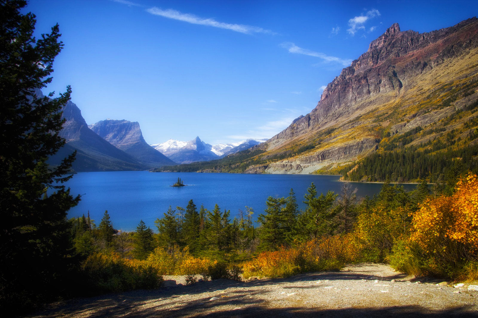 Glacier national park during fall season with fall leaves on bushes in front of lake.