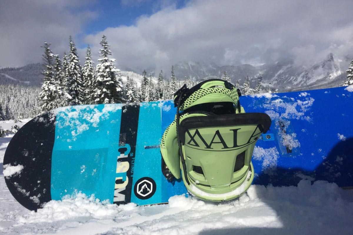 Snowboard propped on snow at top of mountain.