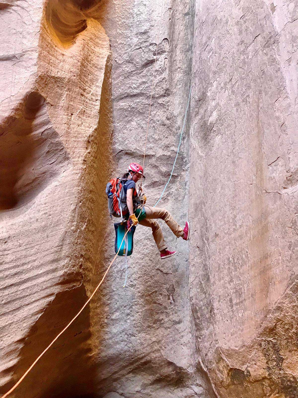 Whitney Thomas rappelling down into canyon.