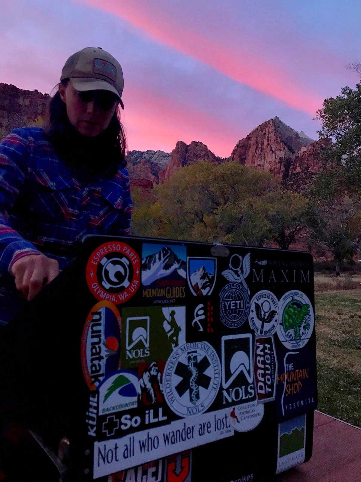 Whitney Thomas cooking dinner at basecamp on a two burner camp stove with a lid covered in stickers.
