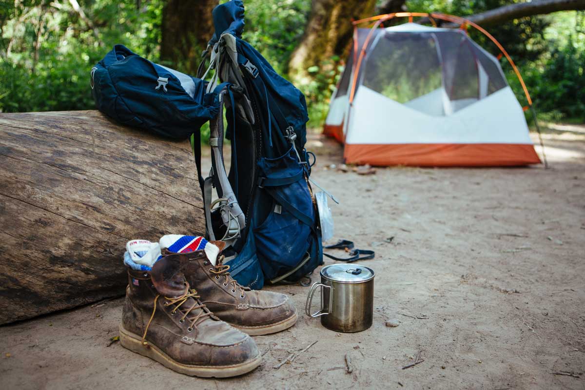 Backpacking gear set out at a campsite with boots and Cloudline Apparel socks in the foreground.