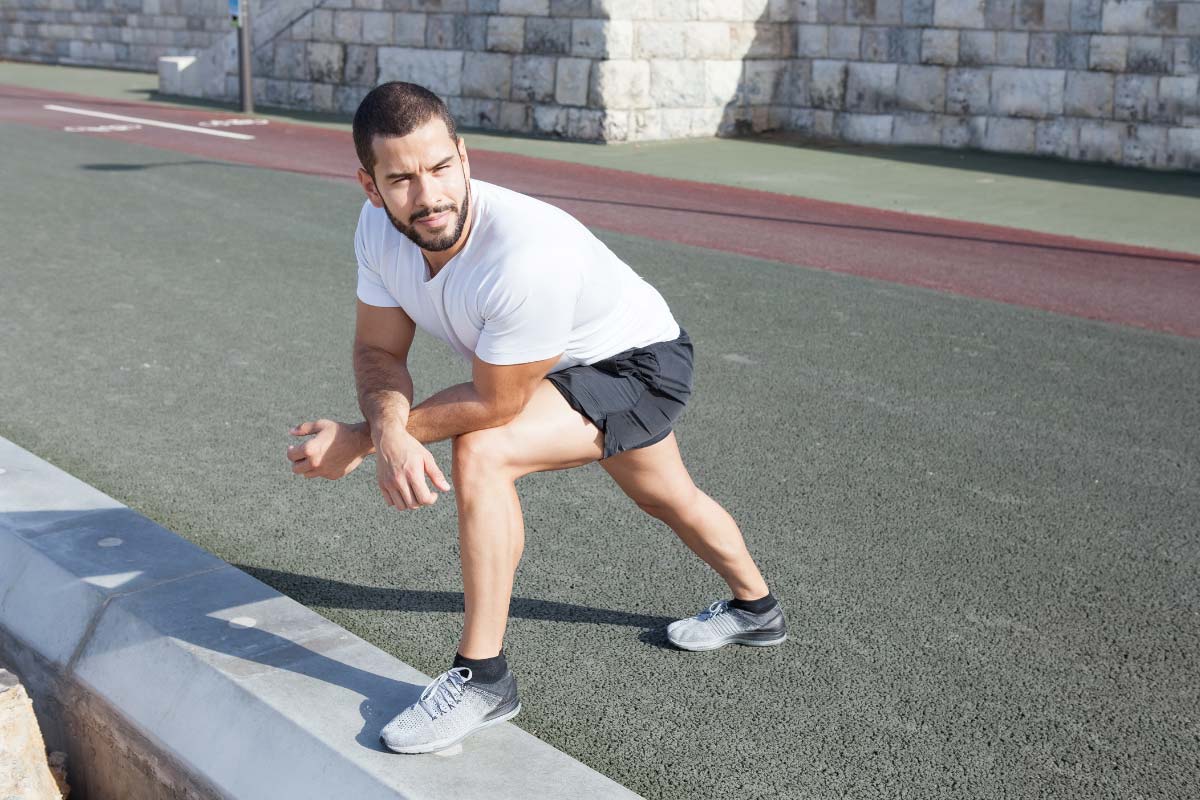 Man stretching his calf on a curb.