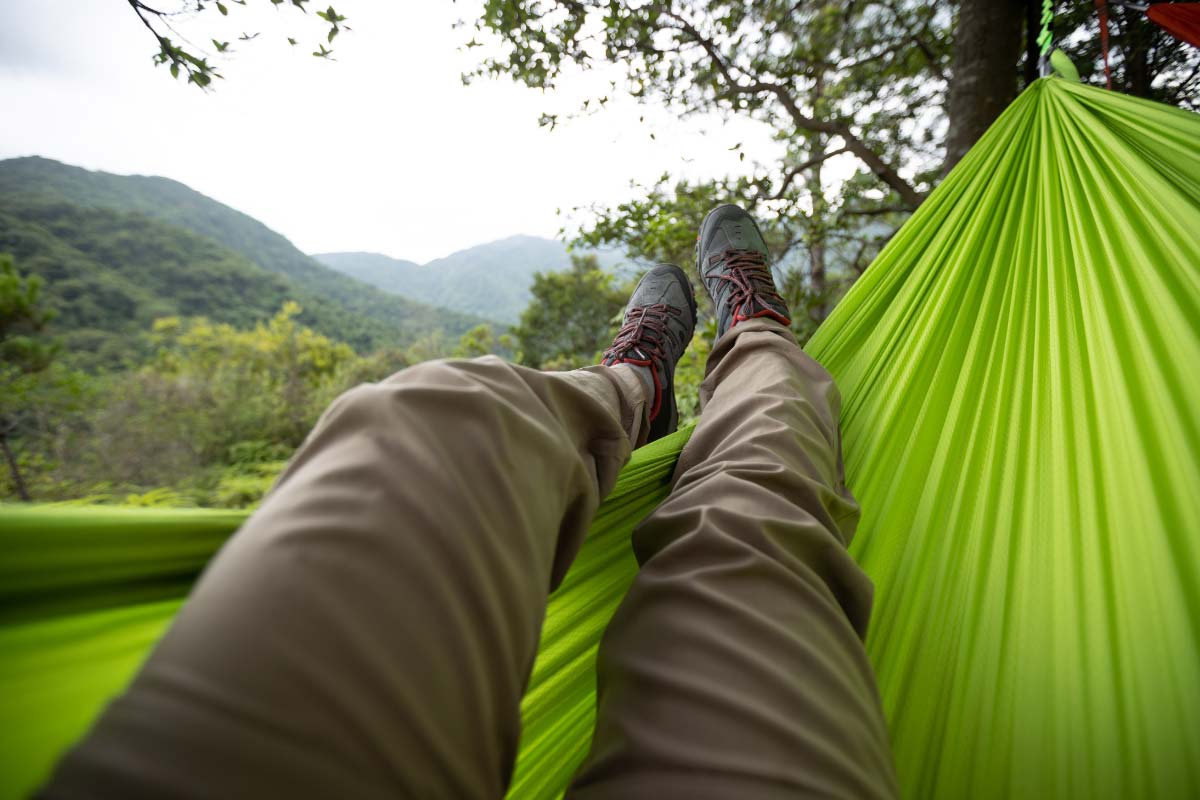 POV of person laying in a neon green hammock with a forested mountain view.