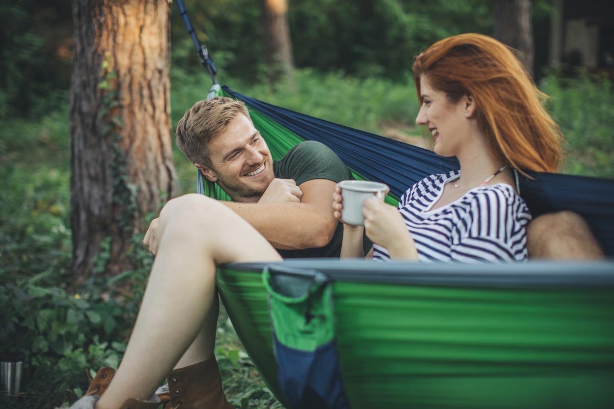 Couple snuggling in a green backpacking hammock.