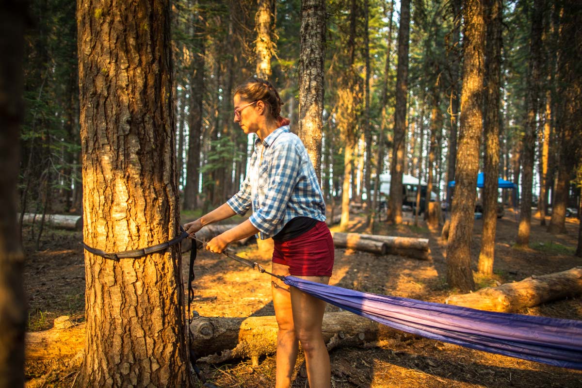 Women hanging a hammock using hammock straps to hang hammock between trees.