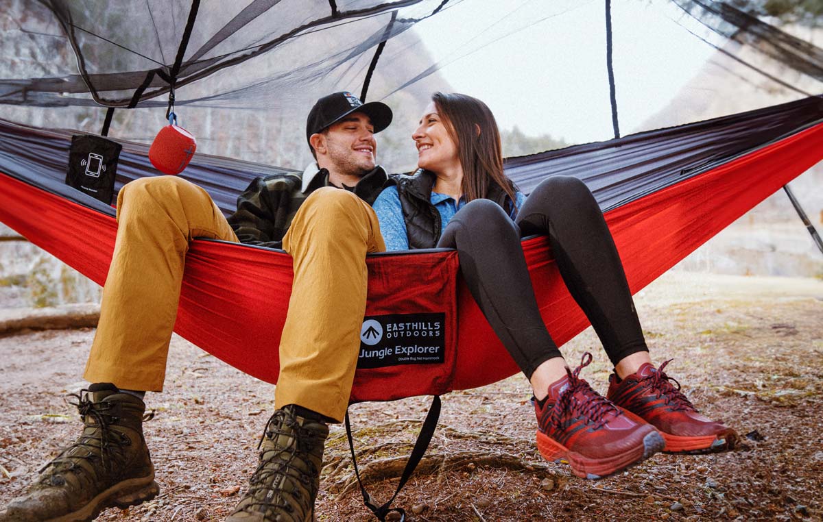 Couple sitting in a hammock with bug net attached.