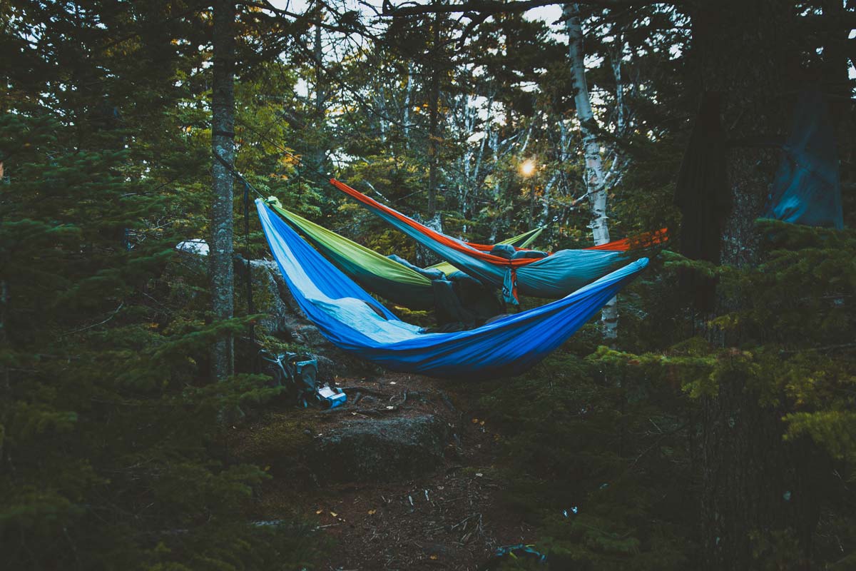 3 hammocks setup with sleeping pads and bags in them.