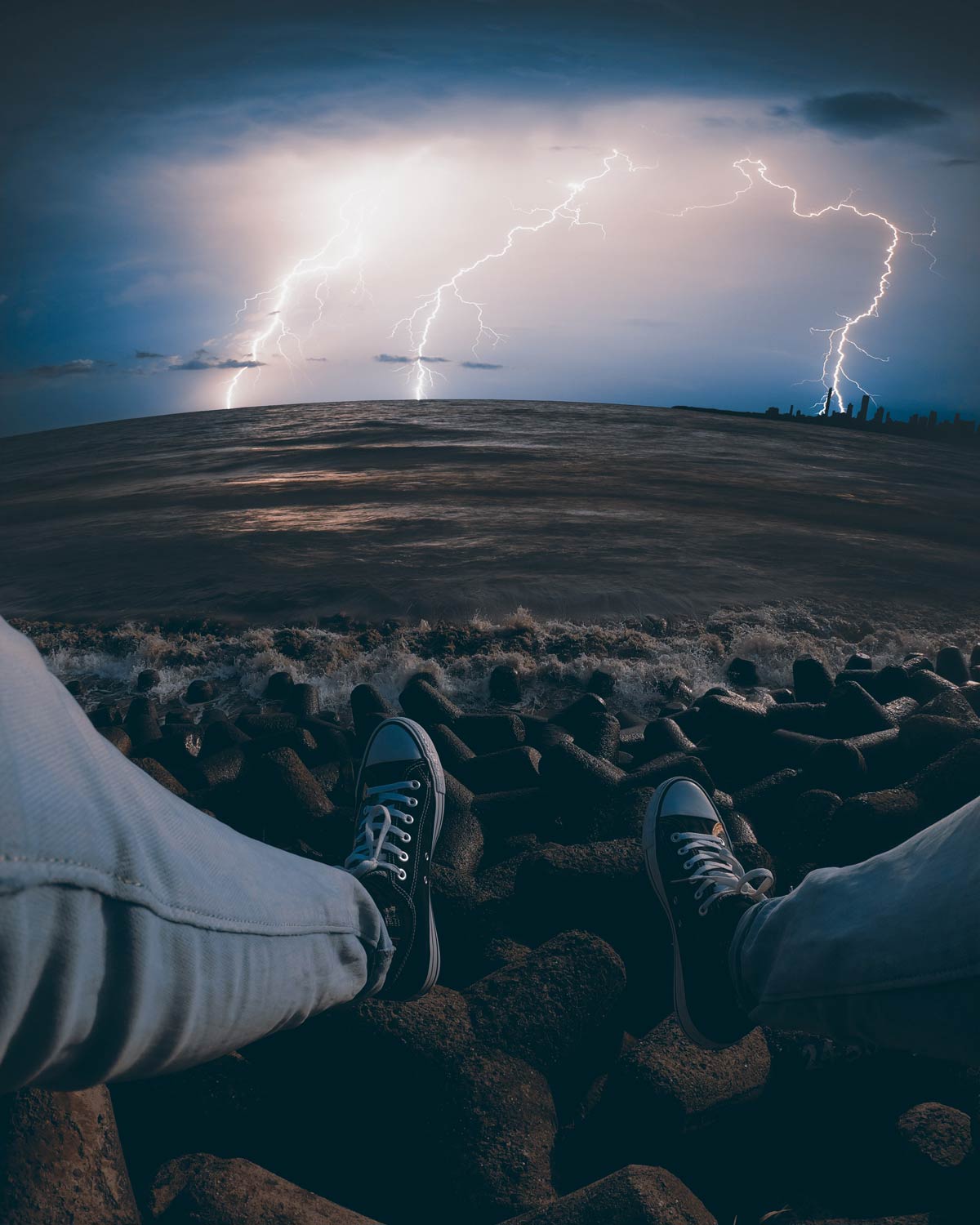 Hiker's view sitting on lake edge during lightning storm.