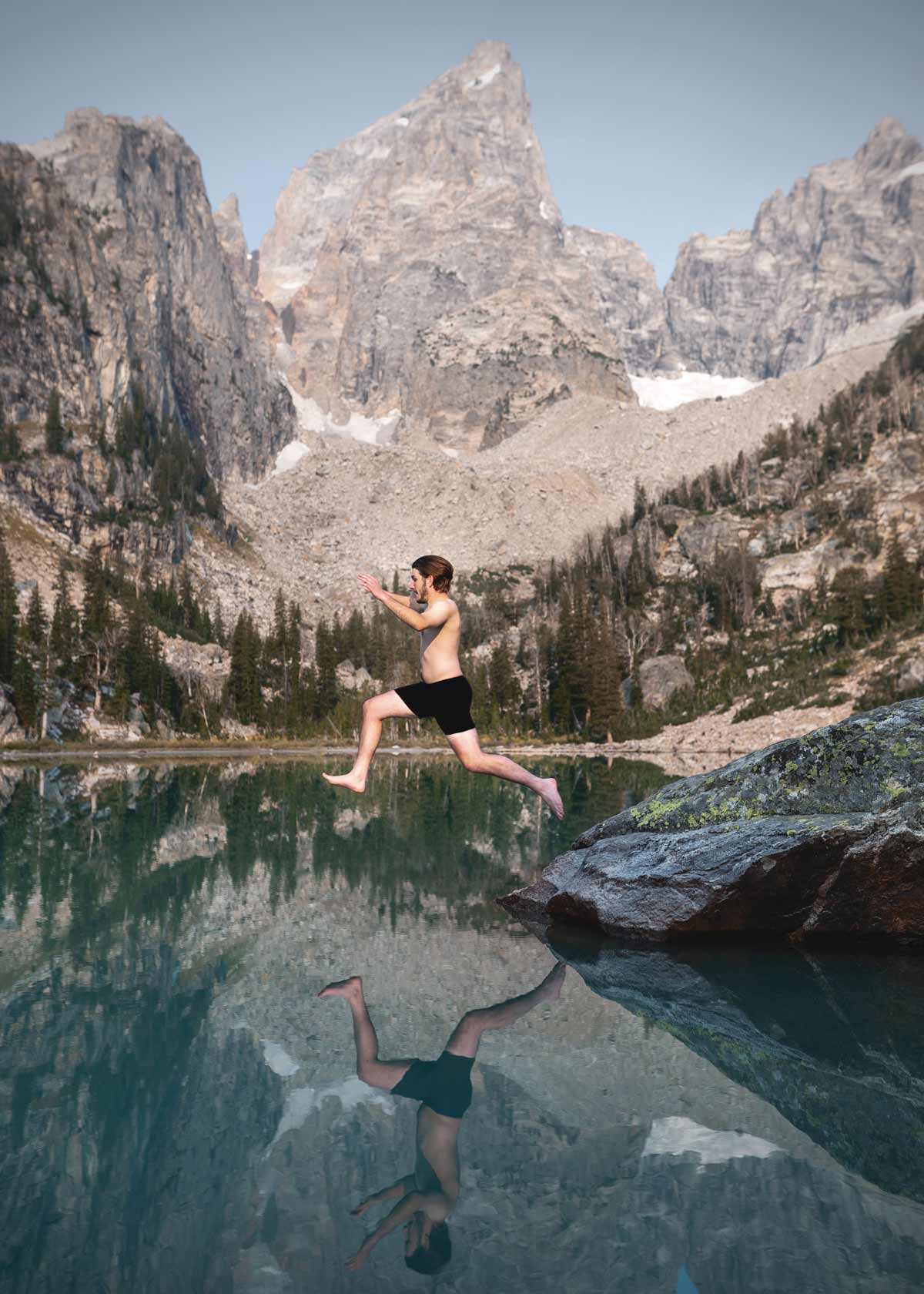 Backpacker jumping in a mountain lake.