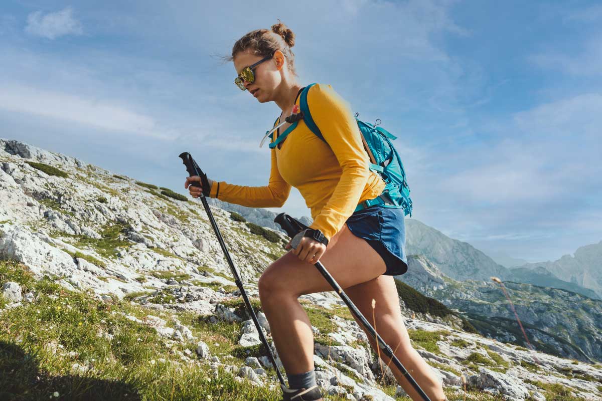 Woman hiking on a hot day with trekking poles.
