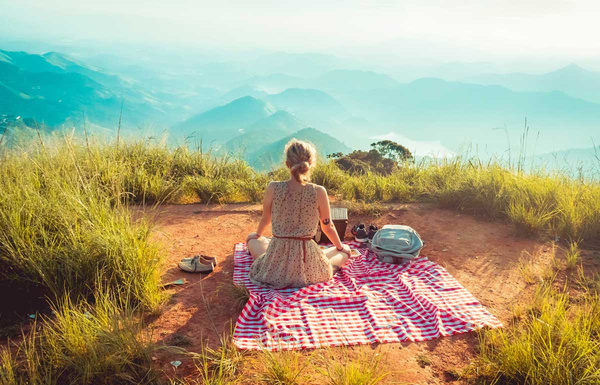 Women sitting on blanket having lunch outside.