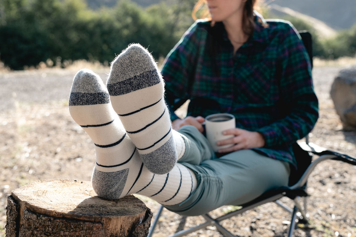 Camper wearing Cloudline Apparel merino wool socks using a log as a foot rest.