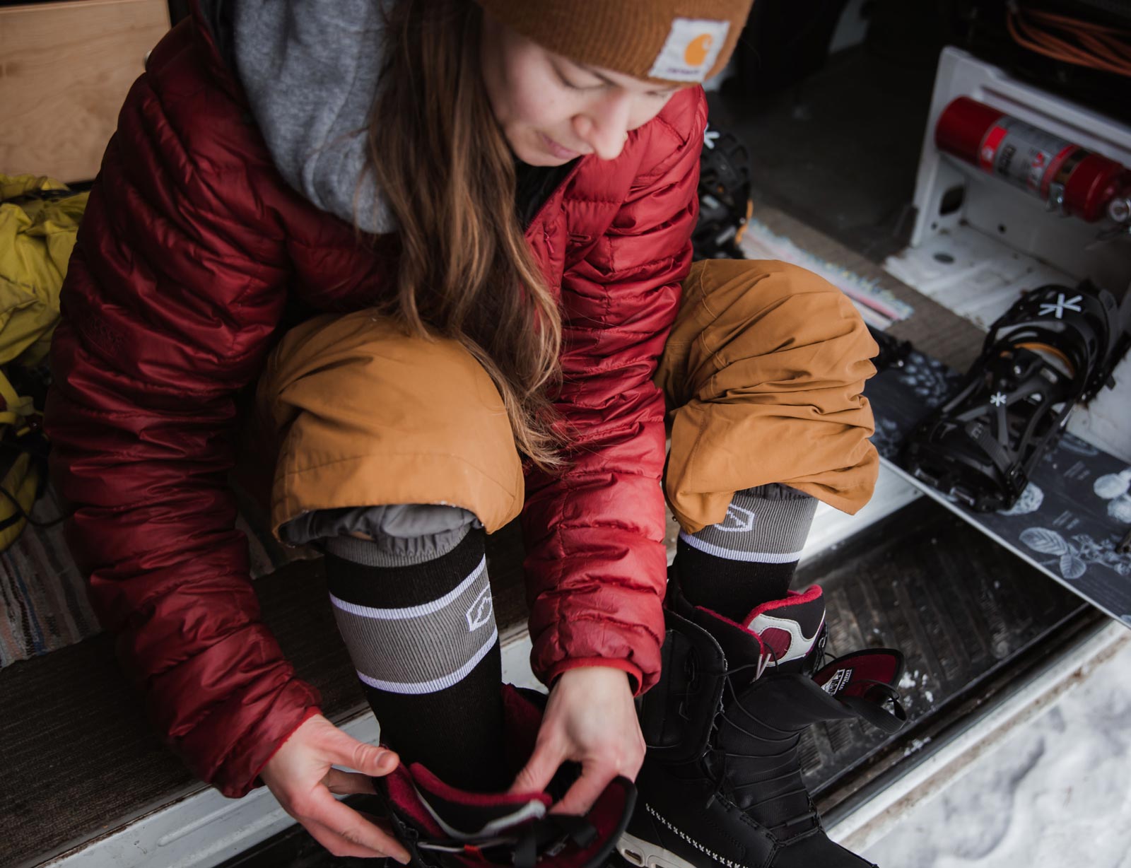 Snowboarder wearing Cloudline snow socks putting on boots.