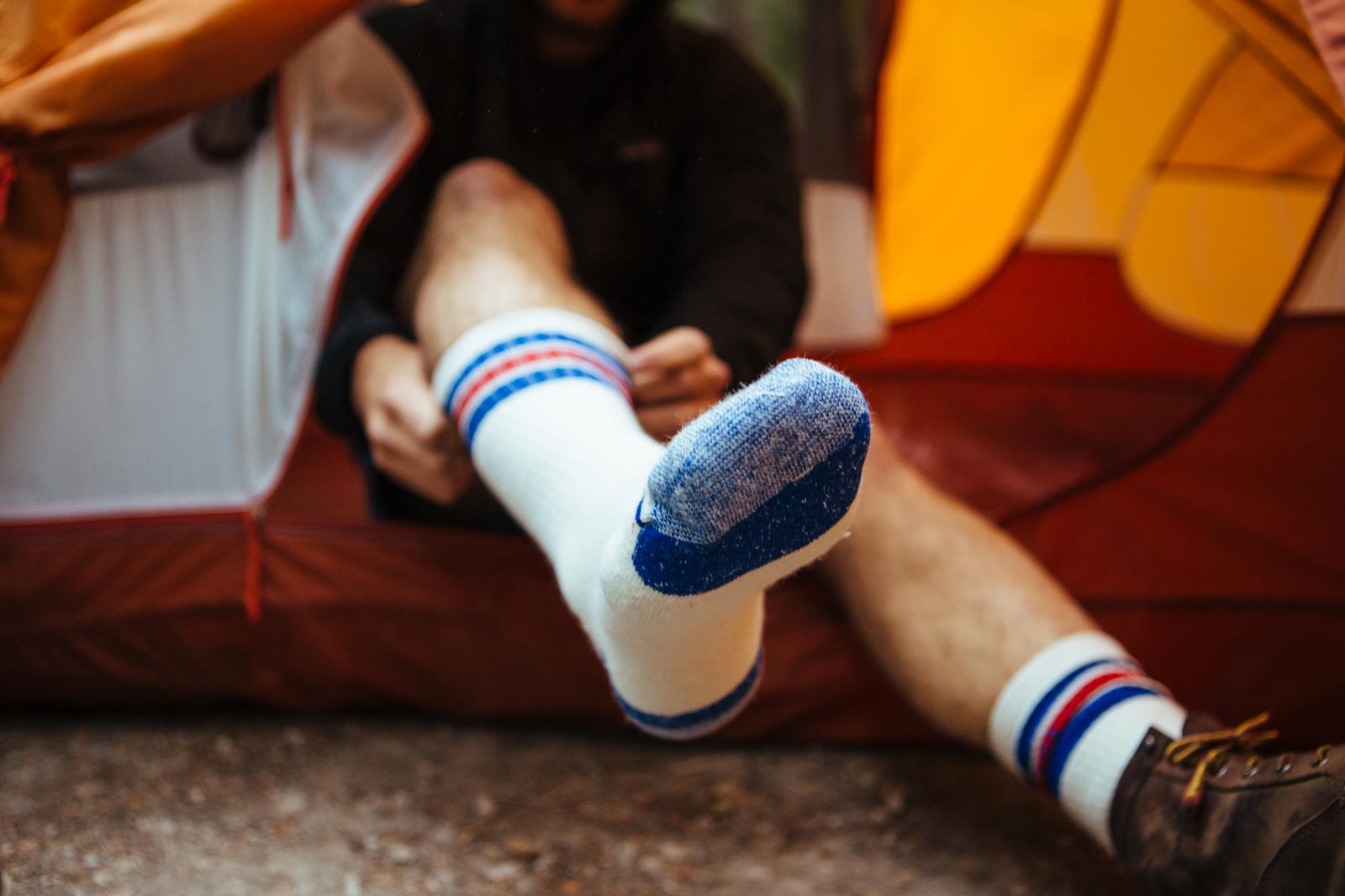Man sitting in tent pulling on Cloudline socks