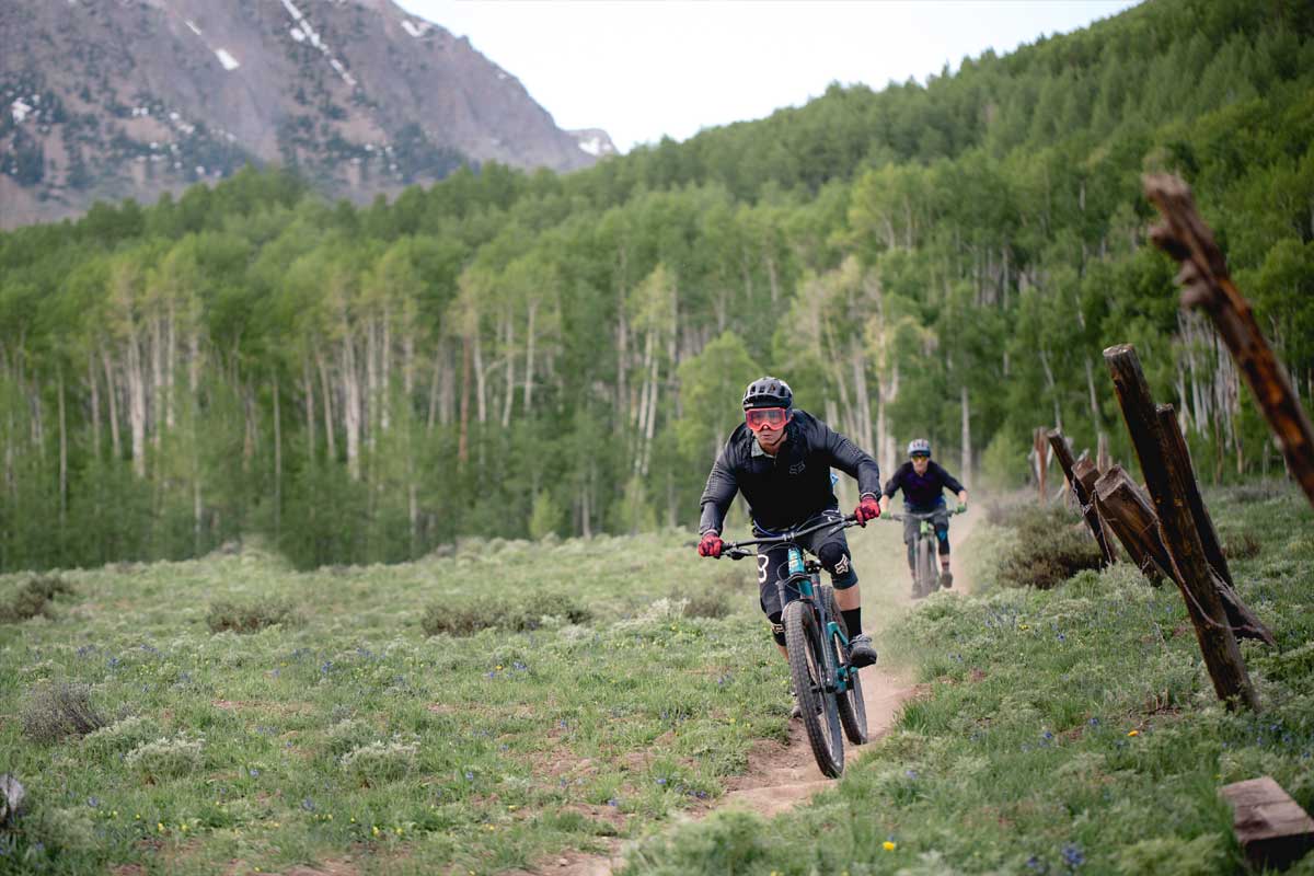 Two mountain bikers riding down a trail in the mountains.