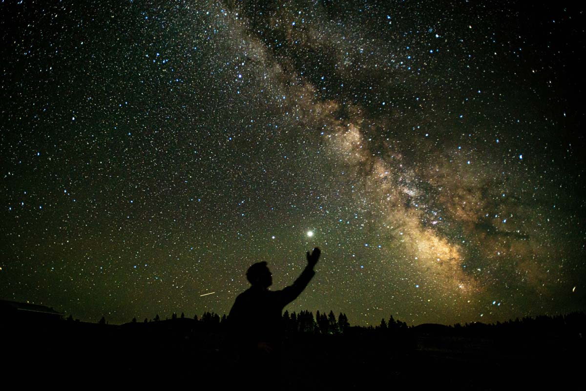 Man standing under a winter night sky filled with brilliant stars.