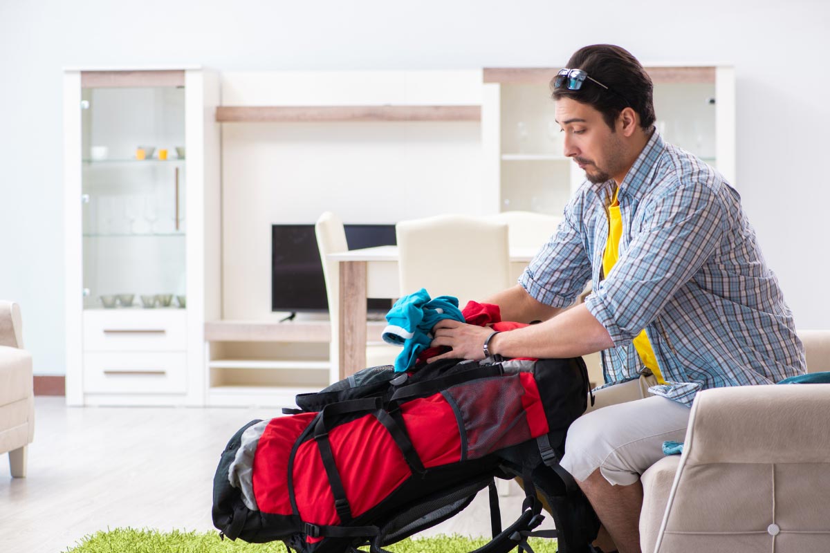 Man packing his backpack at home for a backpacking trip.