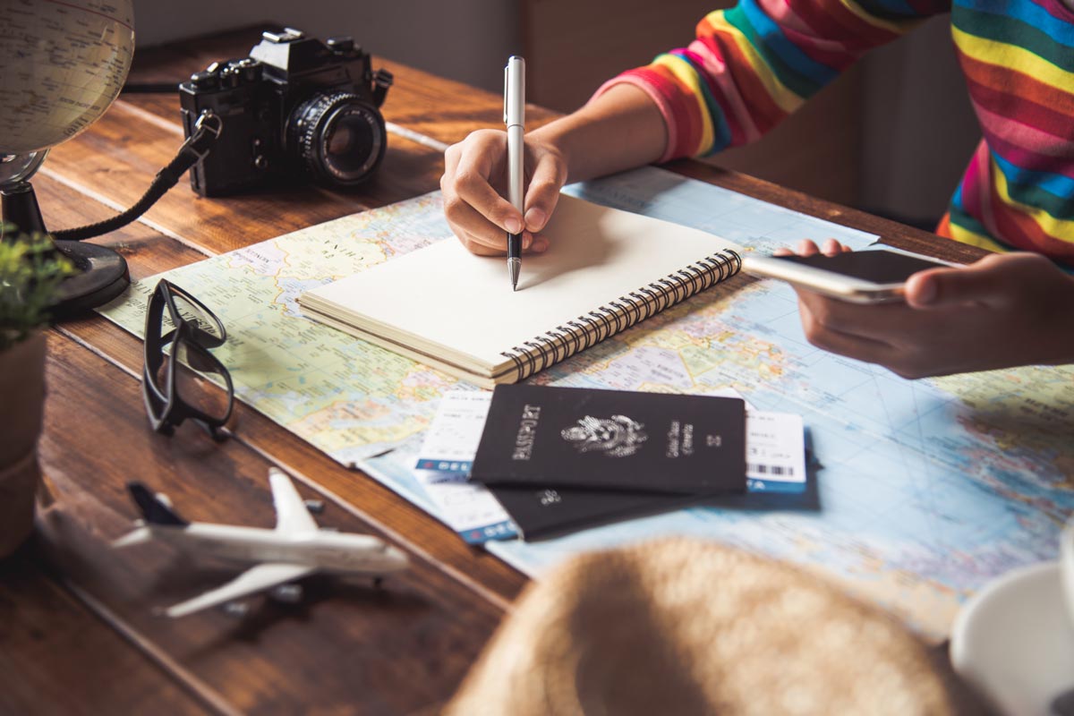 Women at desk using maps and notes to plan a trip.