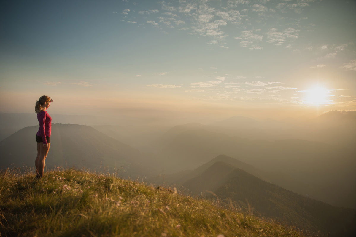 Hiker on mountain top at sunrise to beat the heat.