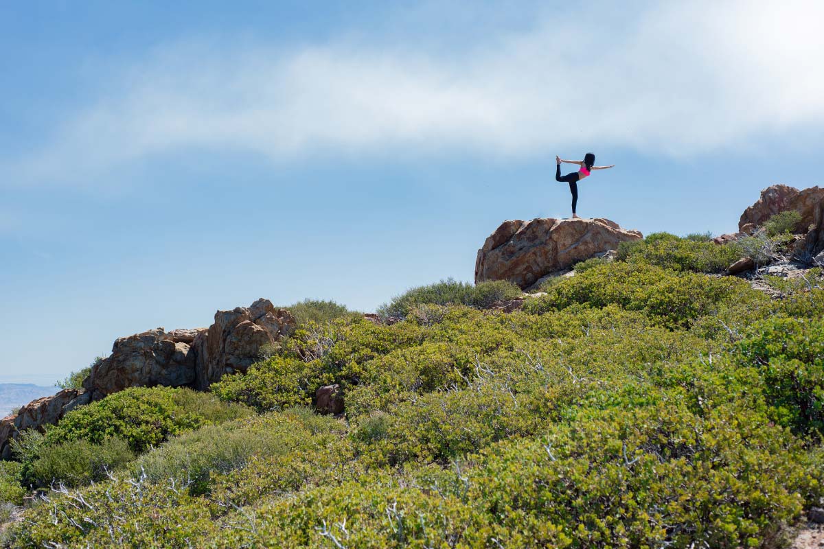 Hiker doing a yoga pose on a mountain top.