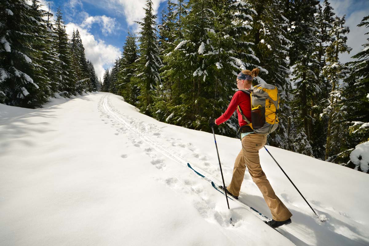 Women with large daypack skiing on trail.