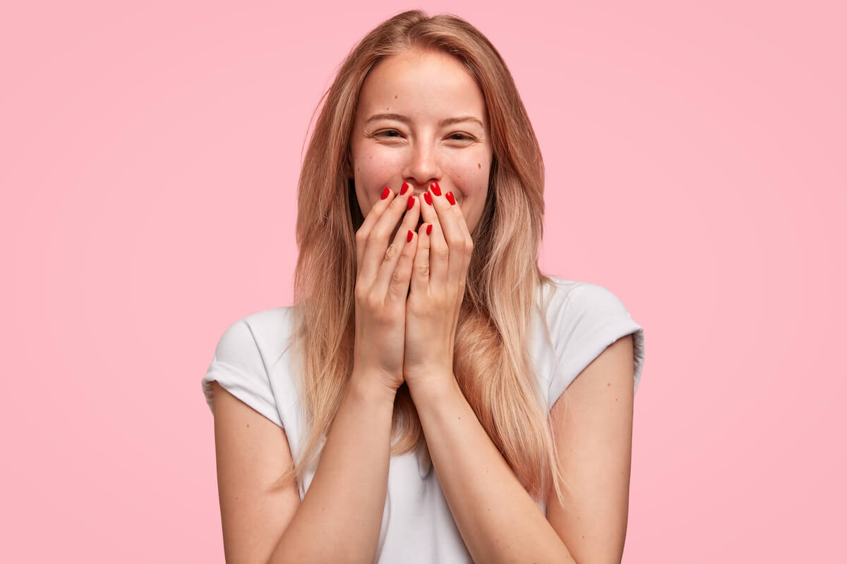 Woman grinning with her hands over her mouth