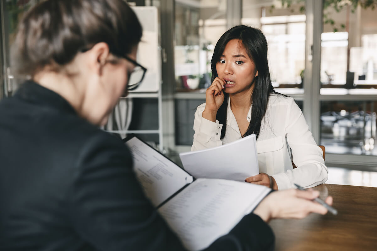 Concerned-looking dark haired woman sitting across the table from another woman. 